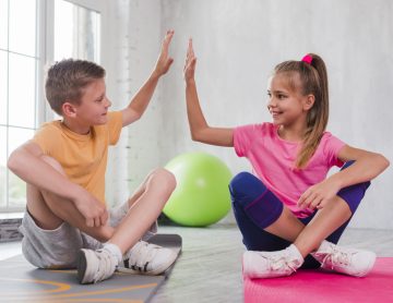 boy-girl-sitting-exercise-mat-giving-high-five